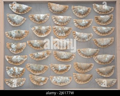 vista dall'alto della pasta fatta in casa - ravioli italiani durante la fase di asciugatura su asciugatrice di noodle Foto Stock