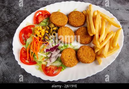 Piatto ovale di patate tradizionali falafel con patatine fritte e insalata. Foto Stock