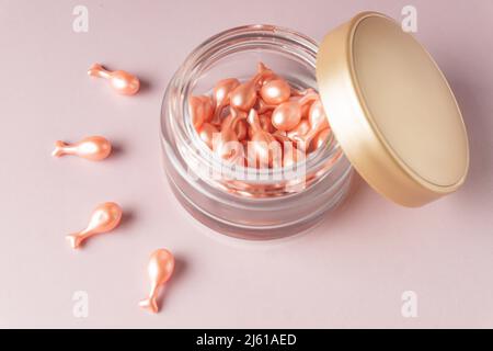 capsule cosmetiche rosa su sfondo rosa spellate da un vaso. Siero o crema monodose per il trattamento della pelle Foto Stock