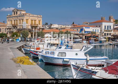 Isola AEGINA Grecia - 4.27.2022: Vista sul mare con barche da pesca nel porto e edifici e case tipiche greche sullo sfondo Foto Stock