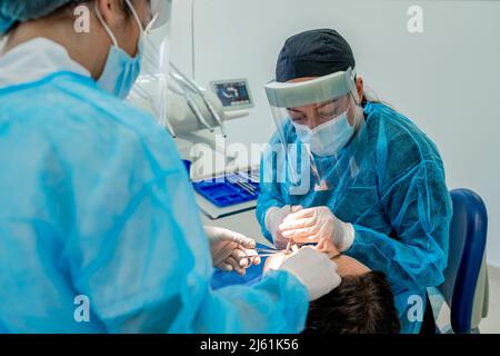 Chirurgo con infermiere che effettua l'intervento chirurgico del paziente in sala operatoria all'ospedale Foto Stock