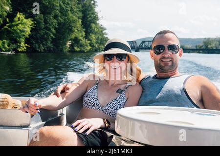 Coppia rilassante con le braccia intorno a vicenda in barca in giorno di sole Foto Stock