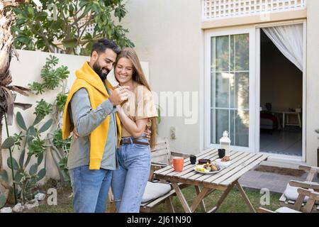 Coppia felice con chiavi in piedi di fronte a casa Foto Stock