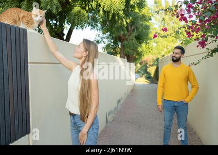 Donna che stroking gatto con l'uomo in piedi dietro Foto Stock