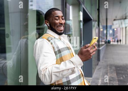 Happy uomo surf rete attraverso smartphone di fronte a parete di vetro Foto Stock