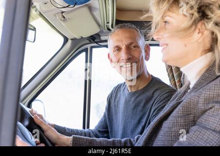 Uomo sorridente a donna che guida un camper furgone Foto Stock