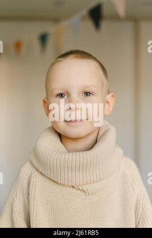 Ragazzo carino sorridente che indossa il maglione dolcevita a casa Foto Stock