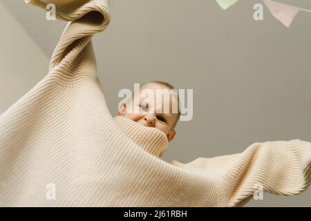 Ragazzo giocoso che indossa un pullover oversize che fa il viso a casa Foto Stock