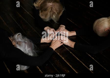 Le donne che tengono le mani inchinandosi sul pavimento a casa Foto Stock