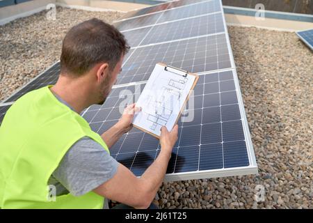 Ingegnere che esamina i pannelli solari con Blueprint Foto Stock