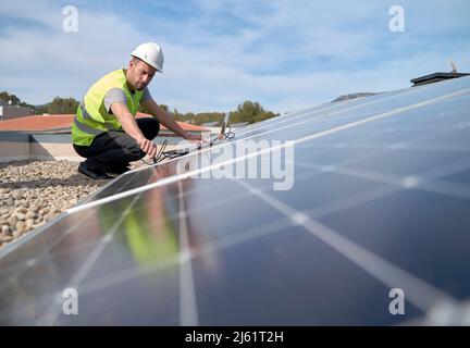 Ingegnere che collega il cavo del laptop ai pannelli solari Foto Stock