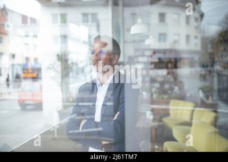 Uomo d'affari che indossa gli occhiali visto attraverso la finestra di vetro Foto Stock