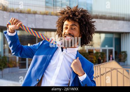 Giocoso uomo d'affari che tira la cravatta davanti all'edificio Foto Stock