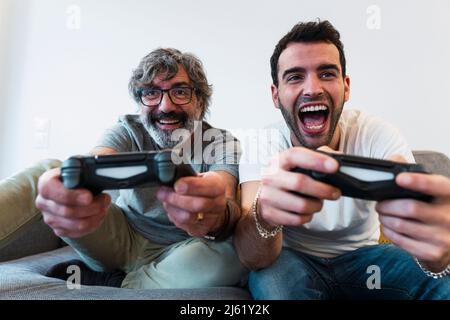 Padre allegro che gioca video gioco con figlio a casa Foto Stock