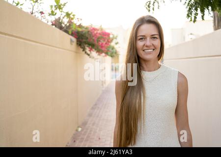 Donna sorridente con lunghi capelli biondi sul sentiero Foto Stock