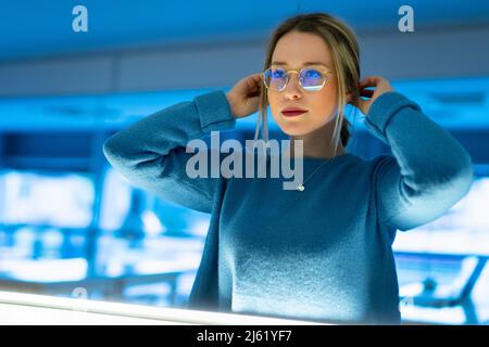Giovane donna con mani in capelli che indossa occhiali Foto Stock