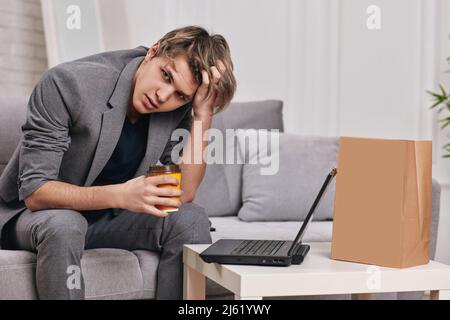 sconvolgessi il giovane caucasico usando il computer portatile a casa Foto Stock