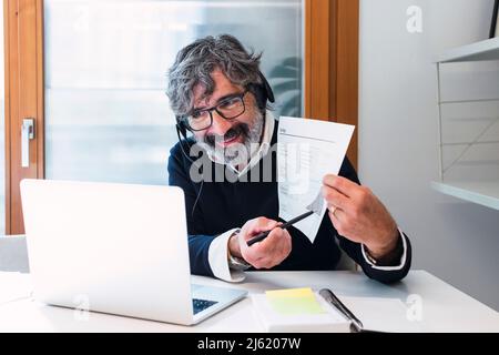 Un freelance sorridente che spiega il documento attraverso una videochiamata sul laptop a casa Foto Stock