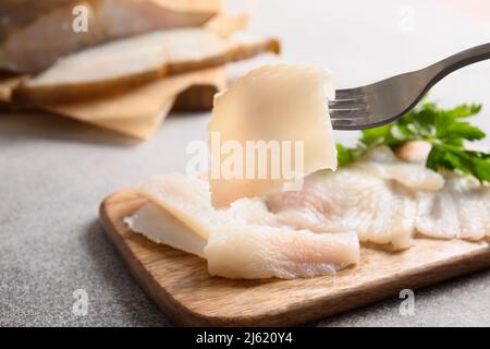 Fette di halibut affumicate su sfondo grigio. Uomo che mangia pesce prelibato. Primo piano. Ricco di grassi sani omega 3 insaturi per chiarezza mentale. Cervello Foto Stock