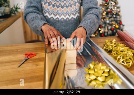 Una giovane donna che avvolge la confezione regalo a casa Foto Stock