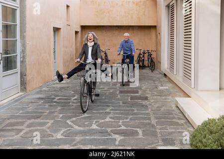 Donna anziana felice in bicicletta con l'uomo sul sentiero Foto Stock