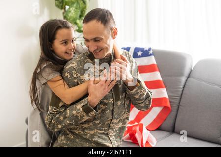 una bambina abbraccia un padre militare, papà in uniforme militare con la figlia, il ritorno del veterano alla famiglia Foto Stock