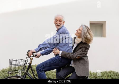 Sorridente donna anziana seduta con uomo a cavallo parete di fronte al muro Foto Stock