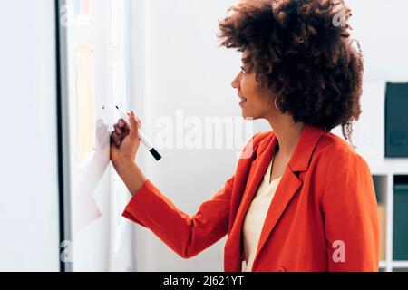 Sorridente imprenditrice scrivere sulla lavagna in office Foto Stock