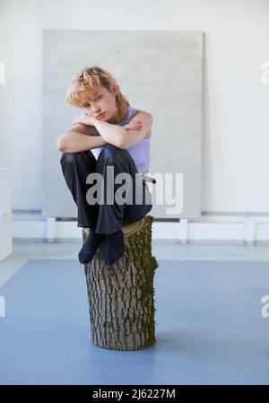 Giovane donna seduta sul log Foto Stock