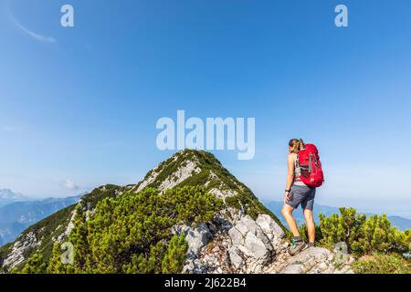 Donna che indossa zaino guardando la montagna in giorno di sole Foto stock  - Alamy