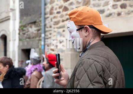 Douarnenez, Francia - Febbraio 27 2022: L'uomo con una maschera Guy Fawkes filma con il suo smartphone durante Les Gras de Douarnenez. Foto Stock