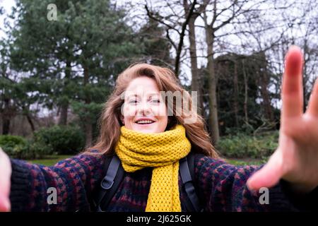 Felice giovane donna in sciarpa gialla godendo in foresta Foto Stock