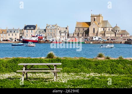 Panchina circondata da fiori in Springtime, Porto di Barfleur, piccola città sulla penisola del Cotentin, Manica, Normandia, Francia Foto Stock