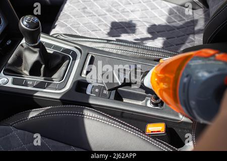 Pulire gli interni di un'auto moderna con un aspirapolvere da sporcizia e polvere, sfondo Foto Stock