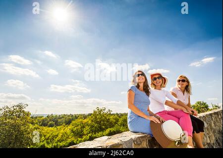 tre donne sedute sul muro di pietra godendo il coutriside Foto Stock