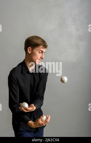 il ragazzo giocoliere si giocolca con tre palle Foto Stock