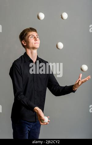 il ragazzo giocoliere si giocolca con tre palle Foto Stock