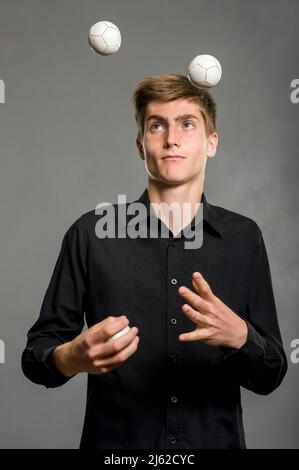 il ragazzo giocoliere si giocolca con tre palle Foto Stock