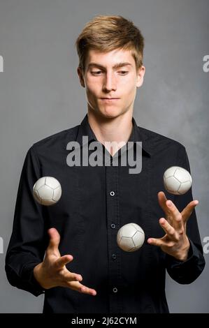 il ragazzo giocoliere si giocolca con tre palle Foto Stock