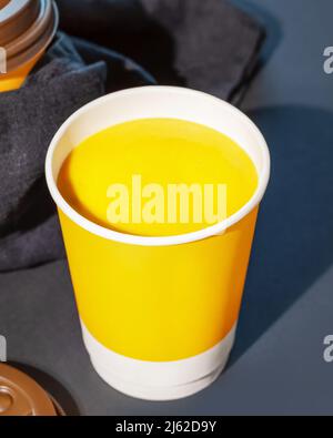 Zuppa naturale densa di crema di zucca vegana con semi in tazza usa e getta su sfondo blu scuro. Concetto di zuppa da andare, take away cibo e cibo sano Foto Stock