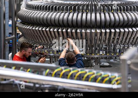 Neutraubling, Germania. 25th Apr 2022. Impiegato Krones AG che lavora su una linea di riempimento in produzione. Credit: Armin Weigel/dpa/Alamy Live News Foto Stock