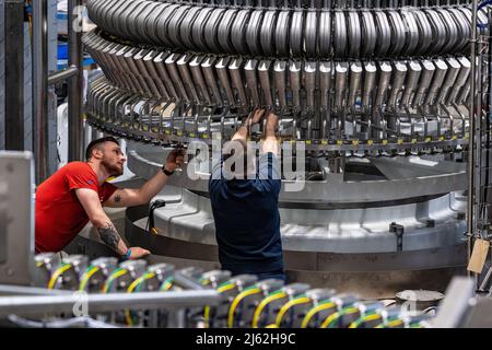 Neutraubling, Germania. 25th Apr 2022. Impiegato Krones AG che lavora su una linea di riempimento in produzione. Credit: Armin Weigel/dpa/Alamy Live News Foto Stock