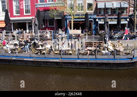 Leeuwarden, Paesi Bassi - 14 aprile 2022: La gente si rilassa e si sorseggia un drink in una caffetteria all'aperto nel centro di Leeuwarden Foto Stock