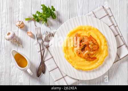 Polenta e schie fritte, piatto veneziano, polenta con gamberi fritti su piatto bianco su tavola di legno con aglio e salsa sullo sfondo, vista orizzontale fr Foto Stock