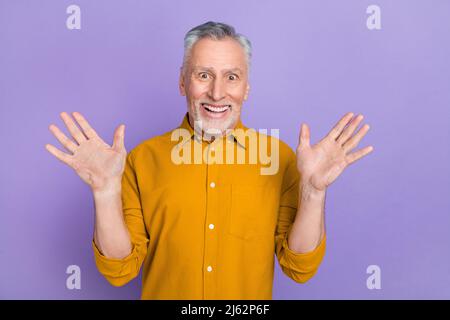 Foto di Hairdo uomo grigio anziano impressionato indossare la camicia di senape isolato su sfondo di colore viola Foto Stock