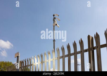 telecamere di sicurezza e acciaio spiked protezione contro un cielo blu vivido Foto Stock