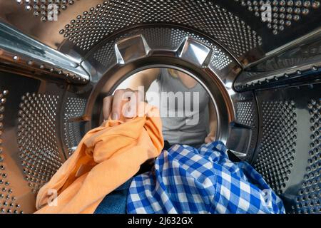 La mano della donna toglie le cose pulite dalla lavatrice, una foto dall'interno. Foto Stock