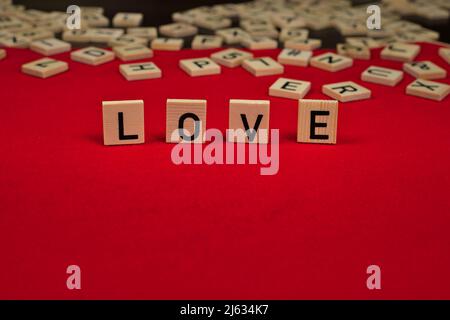 Parola 'Amore' composta da tavole di legno con lettere su sfondo rosso feltro Foto Stock