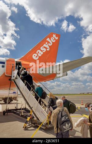 Passeggeri che salono a bordo di un aeromobile easyJet in scalinata dal grembiule dell'aeroporto. Foto Stock