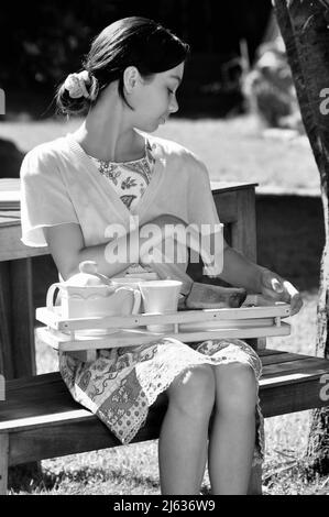 Anni '50 '60 'retro stile italiano Girl in Tea Garden colazione Candid. Nostalgia Foto Stock